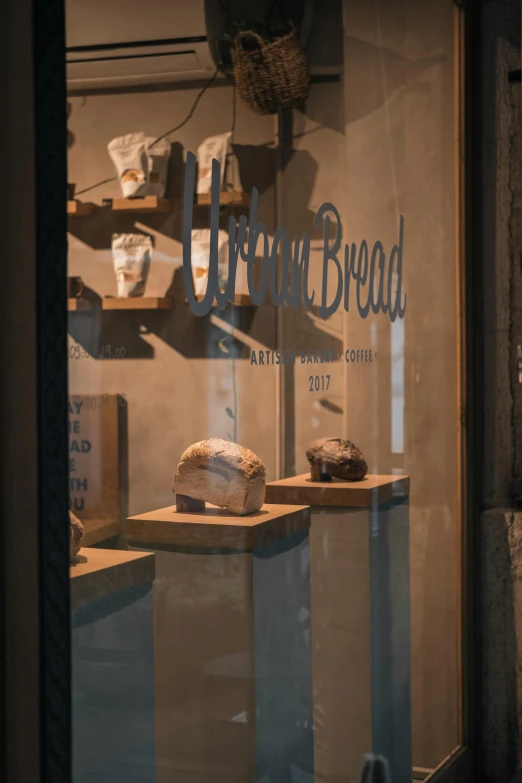 a window that has some bread in it, arte povera, official store photo, head turned, gravels around, lush