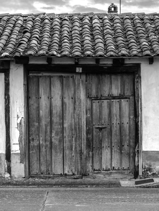 a black and white photo of an old building, by andrei riabovitchev, colombia, wood door, farming, square