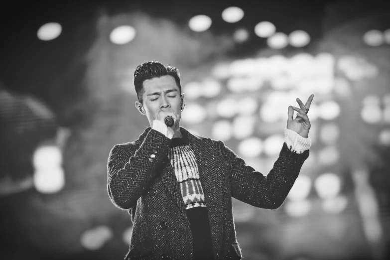 a man standing on top of a stage holding a microphone, a black and white photo, inspired by Guan Daosheng, pexels, wearing a fancy jacket, square, hyung - tae kim, singing for you