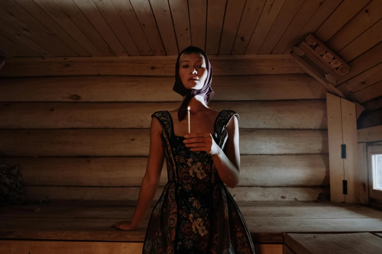 a woman standing in a sauna with a candle in her hand, an album cover, inspired by Vasily Perov, unsplash, renaissance, traditional dress, haute couture fashion shoot, low iso, with a drink