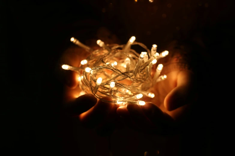 a person holding a string of lights in their hands, full shot photograph, soft coloured gel lighting, lit from above