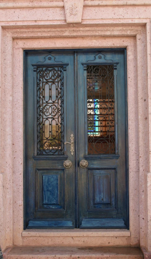 a pair of blue doors sitting on the side of a building, intricate scrollwork, marble and wood and glass, hispanic, square