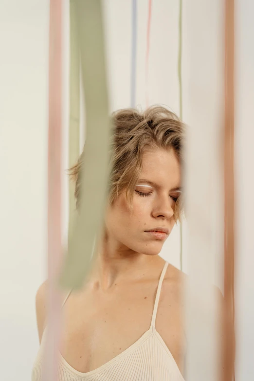 a woman standing in front of a mirror with her eyes closed, by Louisa Puller, trending on pexels, visual art, modern studio light soft colour, parted hair, lines and movement, portrait photo of a backdrop