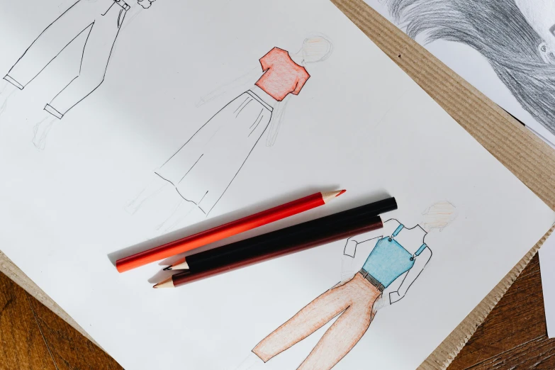 a couple of pencils sitting on top of a piece of paper, a drawing, by Olivia Peguero, trending on pexels, red and blue garments, design your own avatar, orange details, black and red scheme