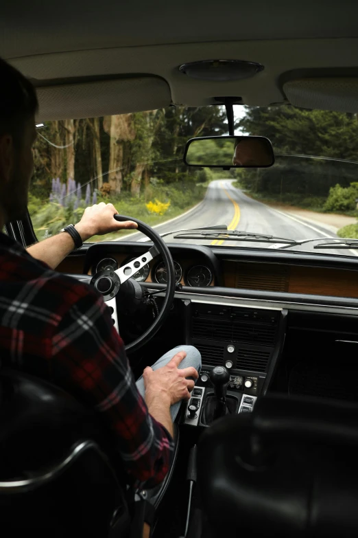 a man driving a car on a country road, by David Donaldson, pexels contest winner, happening, square, leather interior, in the redwood forest, 268435456k film