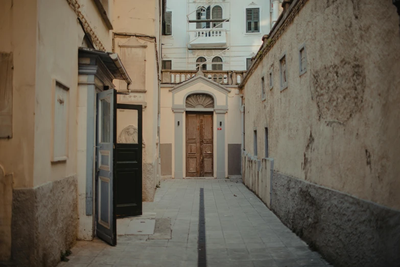 a narrow street with a building in the background, arte povera, symmetrical doorway, cinematic, profile image, overview