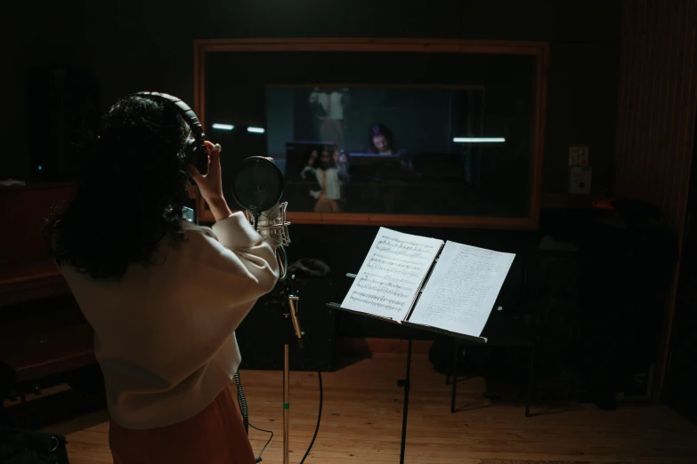 a woman recording music in a recording studio, an album cover, pexels, realism, lorde, 3 / 4 wide shot, sheet music, worship