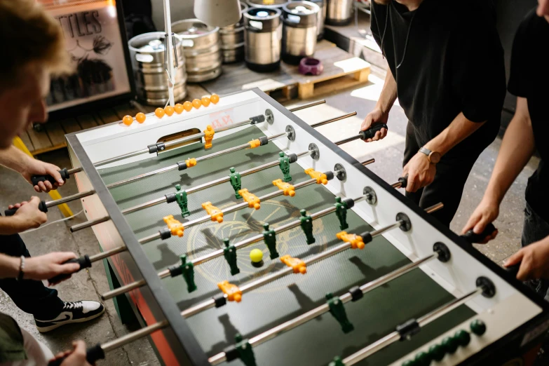 a group of men standing around a foo foo foo foo foo foo foo foo foo foo foo, a silk screen, by Jakob Gauermann, pexels contest winner, board games on a table, football, in a factory, cups and balls