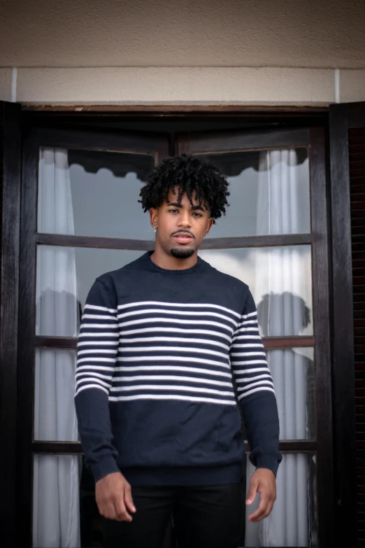 a man standing in front of a window, an album cover, inspired by Theo Constanté, pexels contest winner, striped sweater, aaron brooks, casual pose, headshot