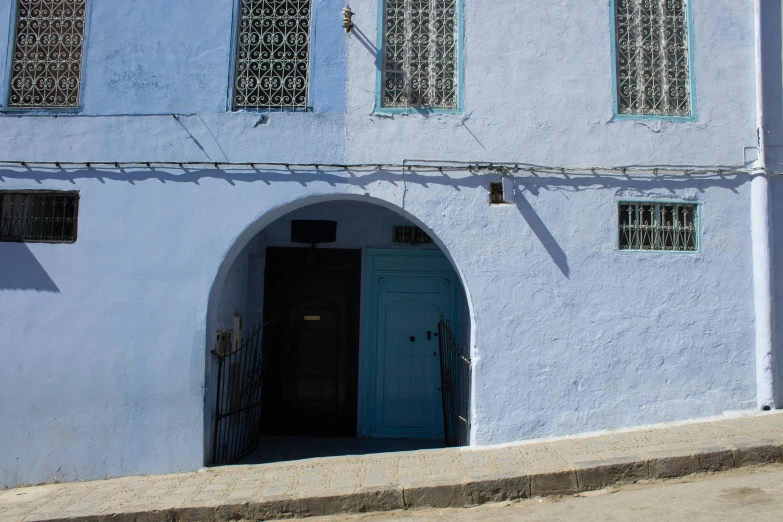 a blue building with a blue door and windows, by Riad Beyrouti, les nabis, built on a steep hill, white and pale blue, thumbnail, storefront