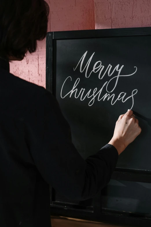 a woman writing merry christmas on a blackboard, by Julia Pishtar, pexels, detail shot, 1 6 x 1 6, a handsome, vertical orientation