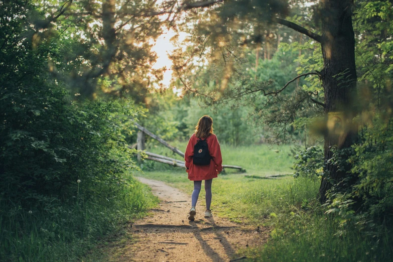 a woman walking down a path in the woods, pexels contest winner, girl watching sunset, wearing a scarlet hoodie, a green, schools