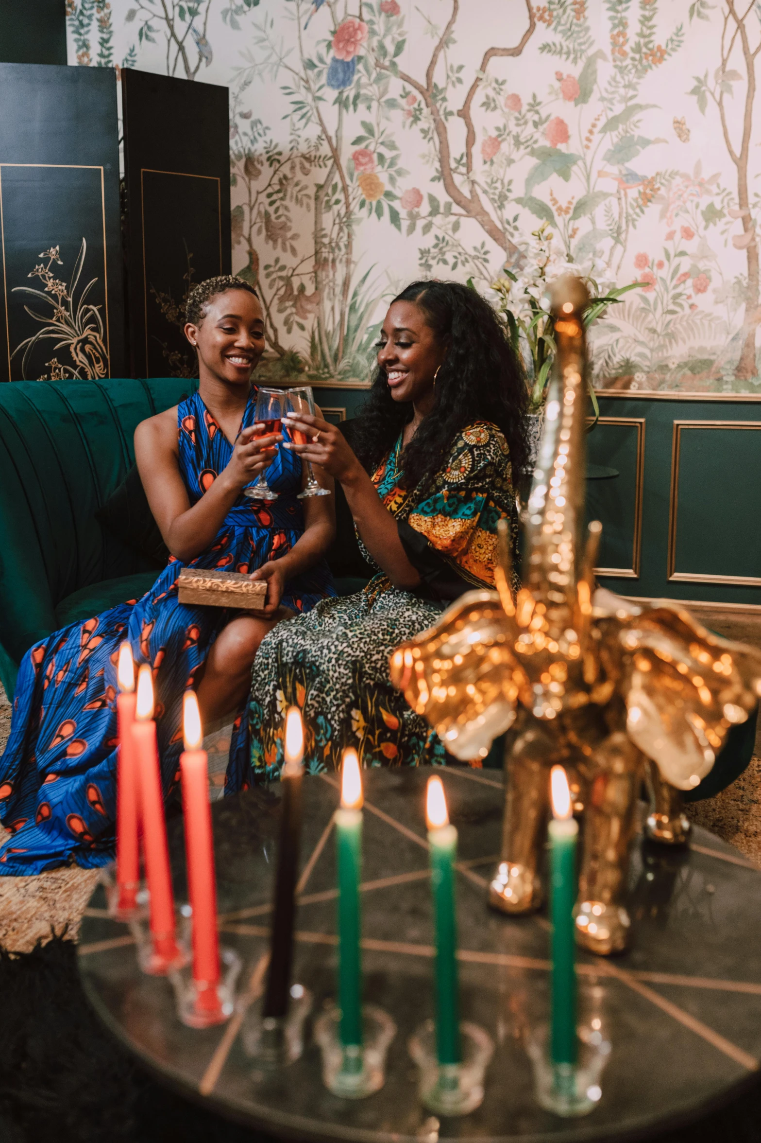 two women sitting on a couch with candles in front of them, trending on unsplash, renaissance, wearing an african dress, cheers, wearing festive clothing, with ivy