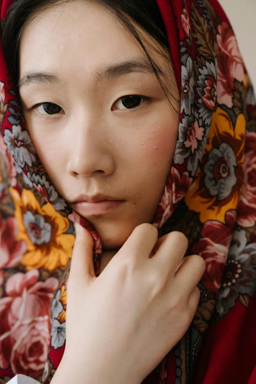 a close up of a person wearing a scarf, inspired by Jin Nong, trending on unsplash, floral clothes, staring at the camera, asian human, modest