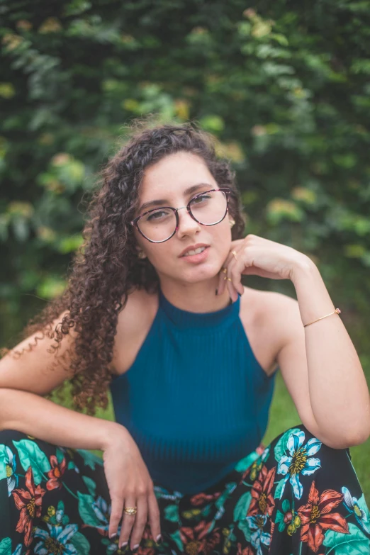 a woman with glasses sitting on the ground, by Julia Pishtar, curly hair, full frame image, square rimmed glasses, hispanic