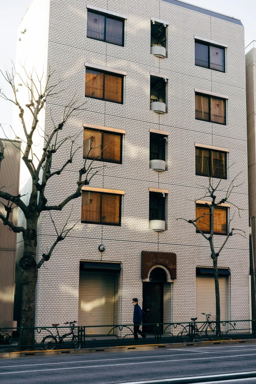 a tall white building sitting on the side of a road, a photo, shin hanga, maison ikkoku, arasaka, late afternoon, street elevation