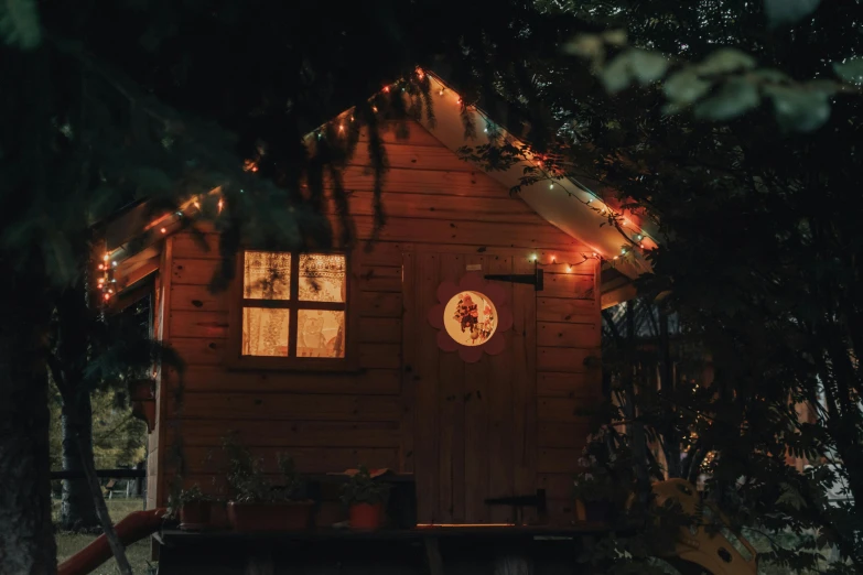 a small cabin is lit up with christmas lights, inspired by Elsa Bleda, pexels contest winner, late summer evening, cottagecore hippie, natural morning light, reddish exterior lighting