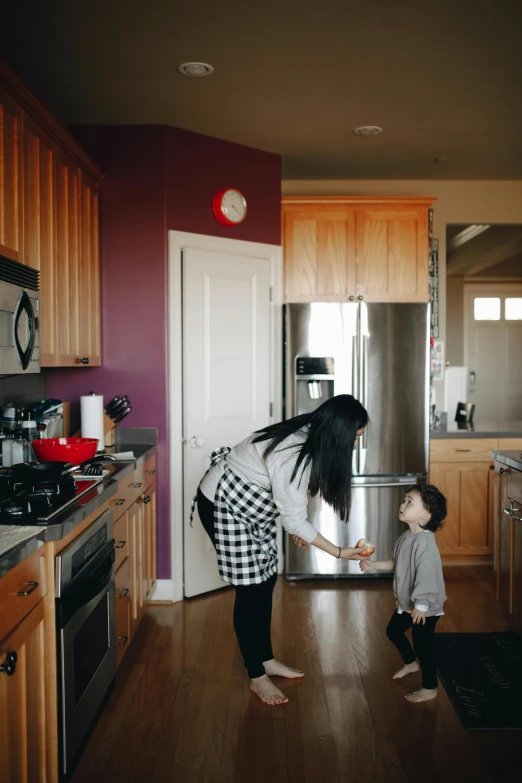 a woman standing next to a child in a kitchen, by Matt Cavotta, pexels contest winner, standing in corner of room, bay area, walking to the right, gif