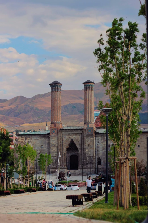 a person sitting on a bench in front of a building, by Muggur, hurufiyya, tall stone spires, huge gate, smelters, in the middle of the city