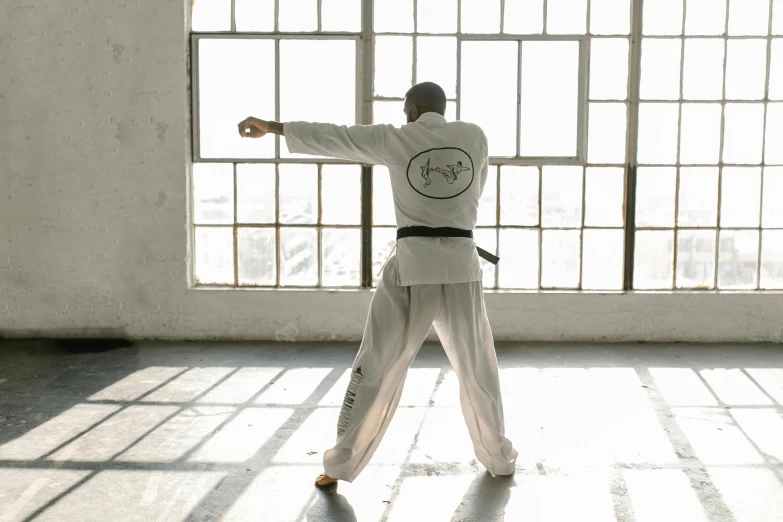 a man that is standing in front of a window, inspired by Ma Quan, unsplash, arabesque, karate outfit, standing in class, white, wearing a tracksuit