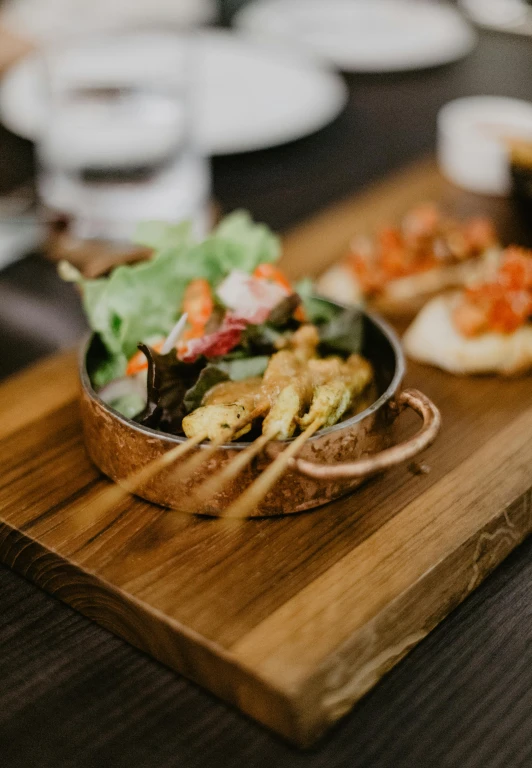 a wooden cutting board topped with food on top of a table, unsplash, gourmet restaurant, caulfield, gold, 1450