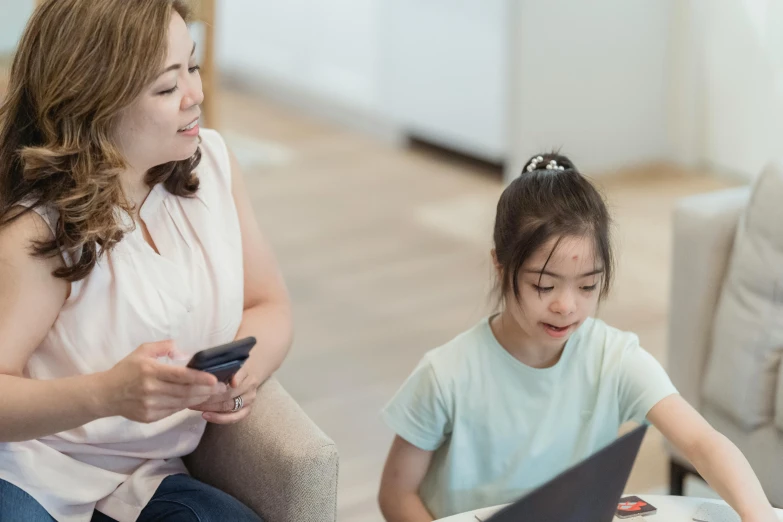 a woman sitting next to a little girl on a laptop, trending on pexels, manuka, avatar image, darren quach, she is holding a smartphone