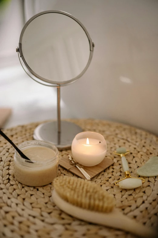 a candle sitting on top of a table next to a mirror, various items, detailed product image, high angle close up shot, light tan