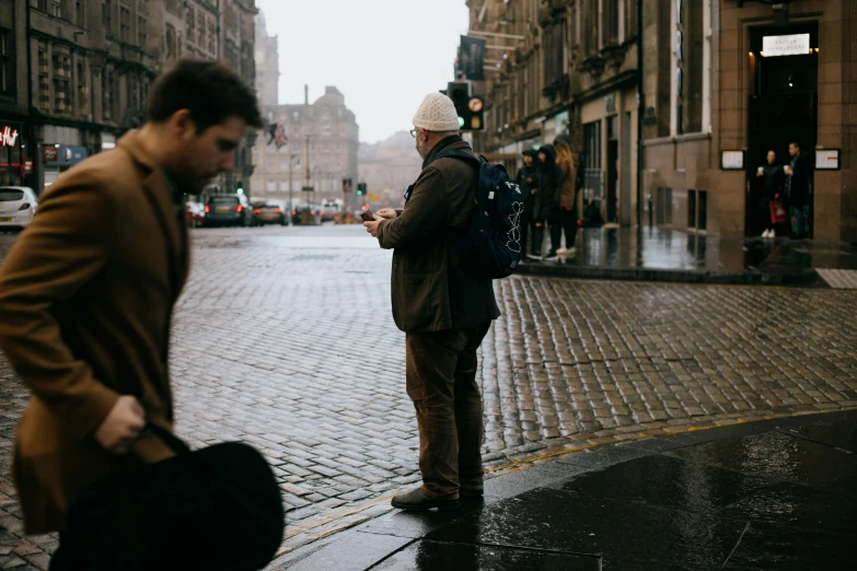 a man standing on a city street looking at his cell phone, by John Murdoch, pexels contest winner, in scotland, group of people, poop, slight overcast