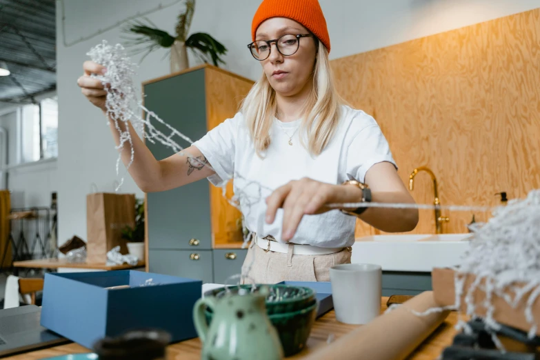 a woman that is standing in a kitchen, process art, crafts and souvenirs, pouring, string art, wearing small round glasses