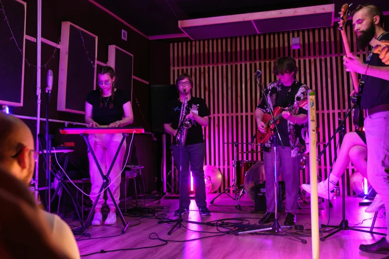 a group of people standing on top of a wooden floor, an album cover, unsplash, private press, performing on stage, neon basement, 3 jazz musicians, slight overcast lighting