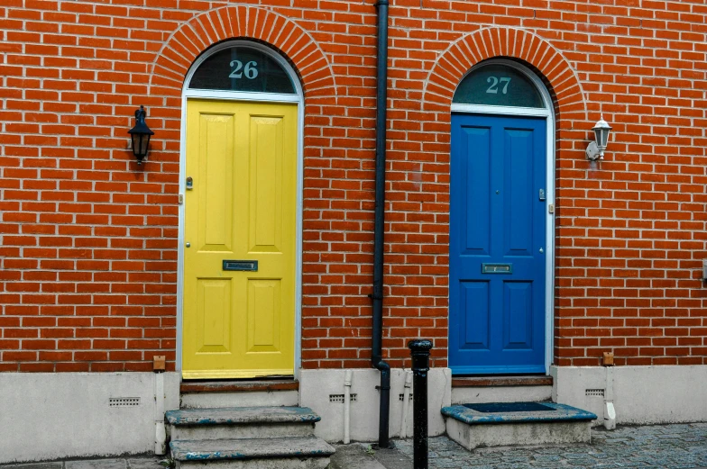 a red brick building with two blue and yellow doors, inspired by L. S. Lowry, unsplash, multicolored, residential, door, terraced