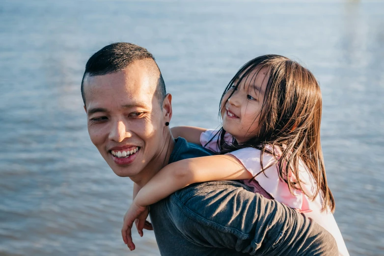 a man holding a little girl by the water, pexels contest winner, asian descent, avatar image, smiling confidently, thumbnail