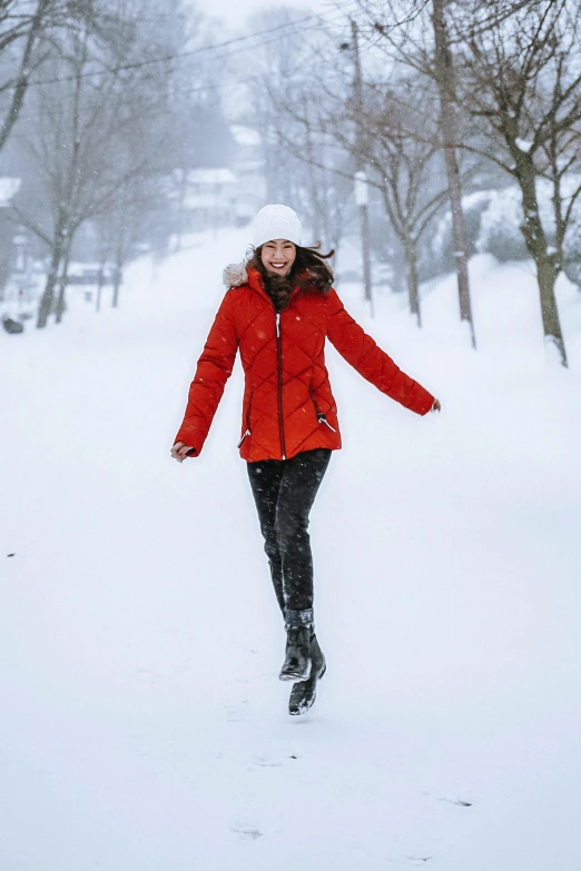 a woman in a red jacket is running through the snow, by Julia Pishtar, stockholm, looking happy, [ cinematic, red hat