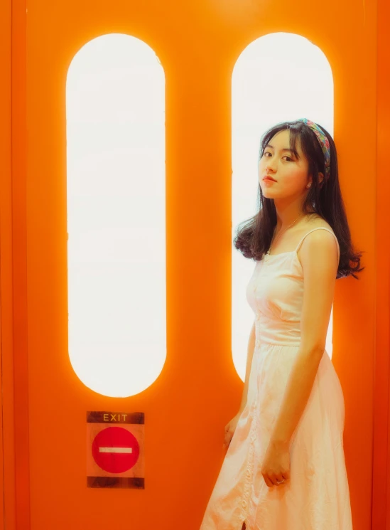 a woman standing in front of an orange door, a picture, inspired by Kim Jeong-hui, pexels contest winner, realism, wearing a cute white dress, 🤤 girl portrait, ulzzang, in an elevator