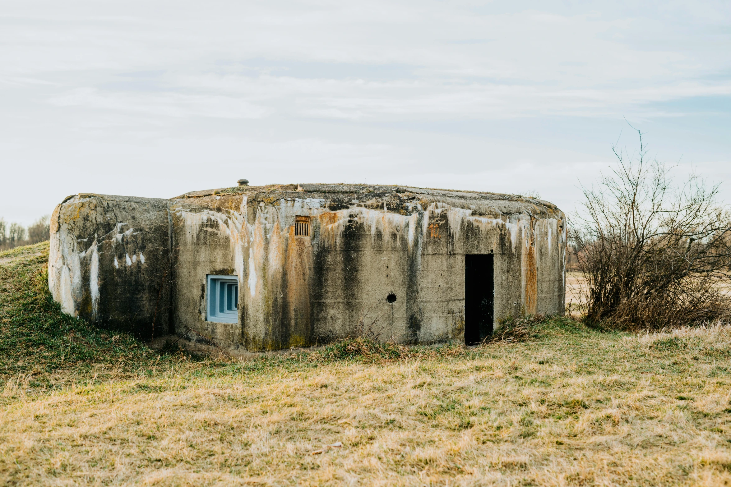 a concrete structure sitting on top of a grass covered field, a portrait, by Emma Andijewska, unsplash, bunkers, 1940s photo, fortresses, everything enclosed in a circle