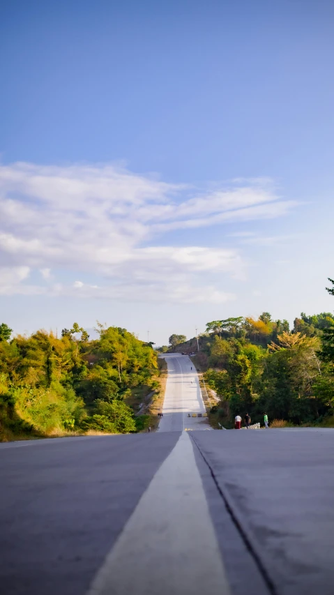 a man riding a skateboard down the middle of a road, mingei, ultrawide landscape, hill with trees, okinawa japan, slide show