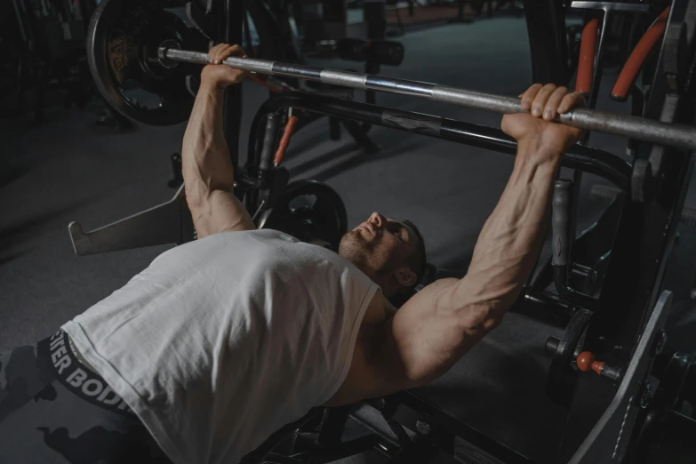 a man doing a bench press in a gym, a screenshot, by Adam Marczyński, pexels contest winner, manuka, chiseled, lee griggs, local gym