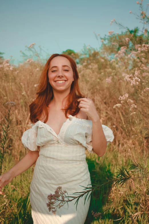 a woman in a white dress standing in a field, an album cover, inspired by Elsa Bleda, pexels contest winner, renaissance, happily smiling at the camera, a redheaded young woman, wearing a camisole, better known as amouranth