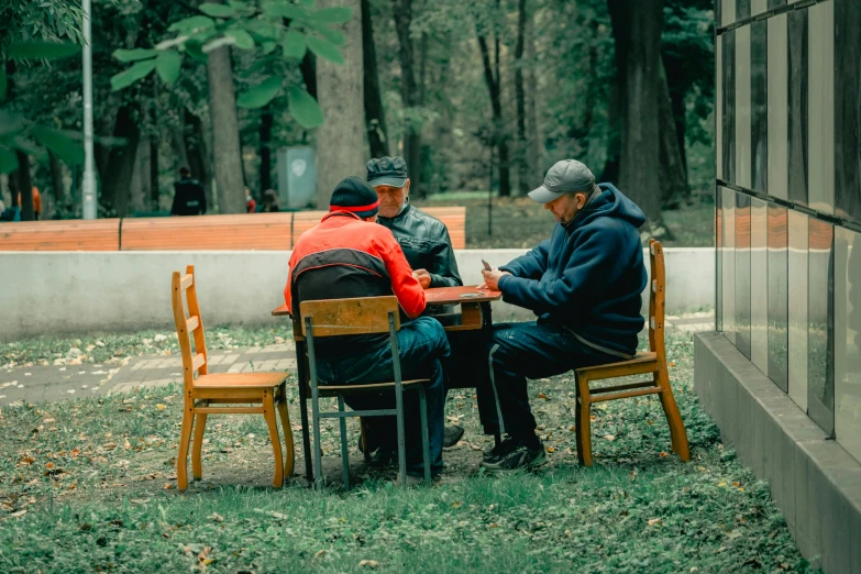 two men sitting at a table in a park, by Adam Marczyński, pexels contest winner, game board, two old people, of a family standing in a park, a group of people