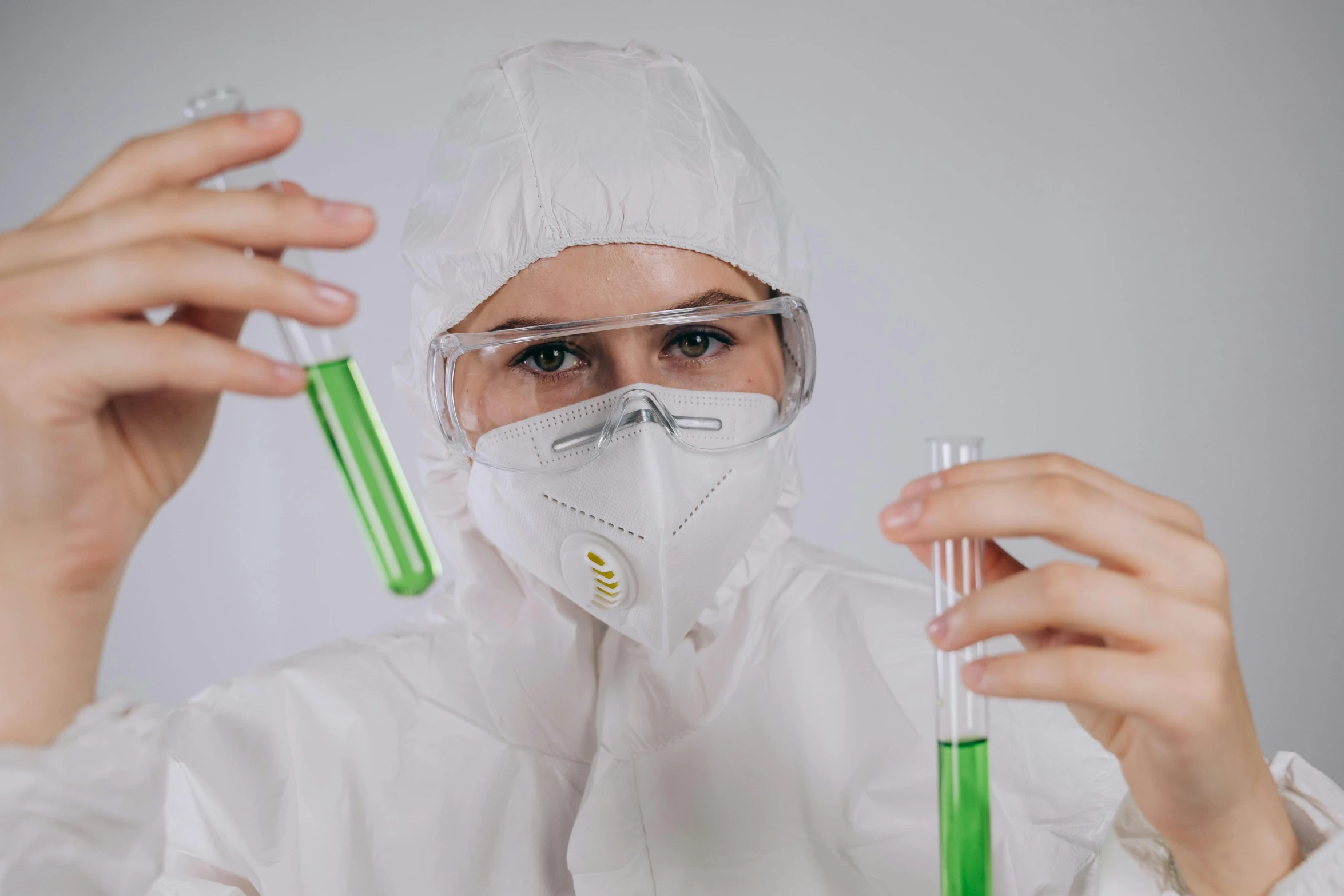 a woman in a lab coat holding two test tubes, pexels, analytical art, a green, biopunk suit, girl wearing uniform, white