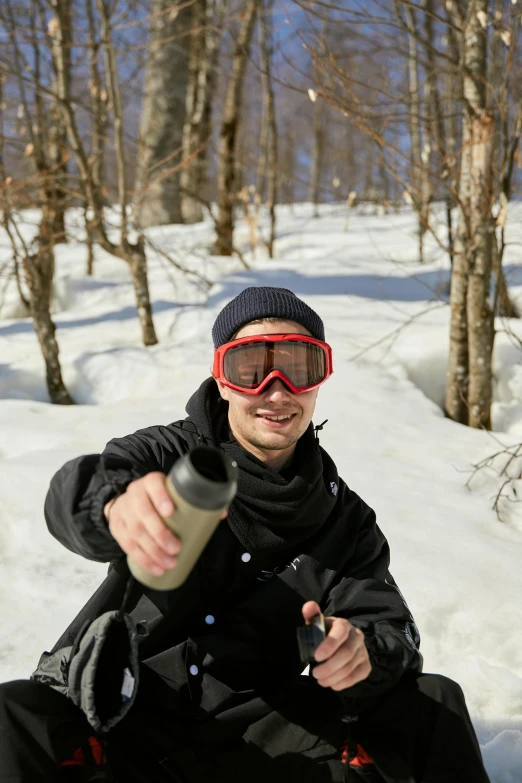 a man riding a snowboard down a snow covered slope, holding flask in hand, pointing at the camera, 2019 trending photo, birch