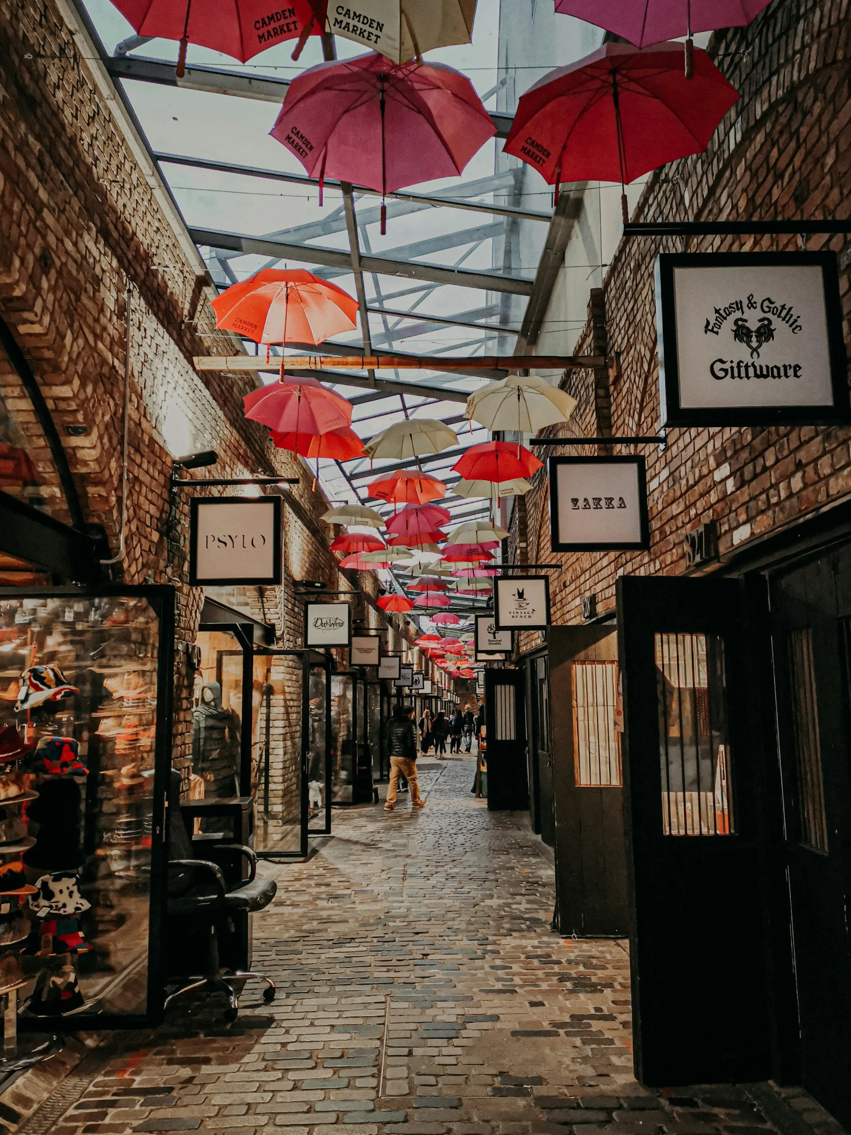 a street filled with lots of umbrellas hanging from the ceiling, in chippendale sydney, black and red colour palette, cobblestone streets, an escape room in a small