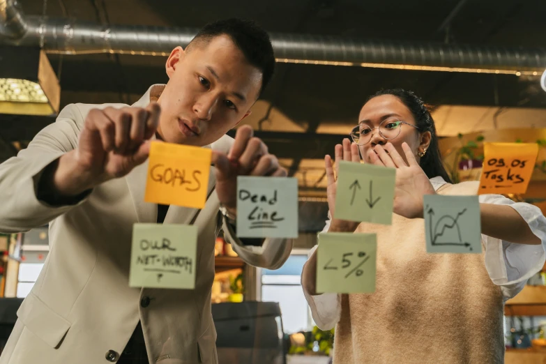 a man and a woman holding up post it notes, pexels contest winner, ruan jia and brom, working hard, 🦑 design, asian man