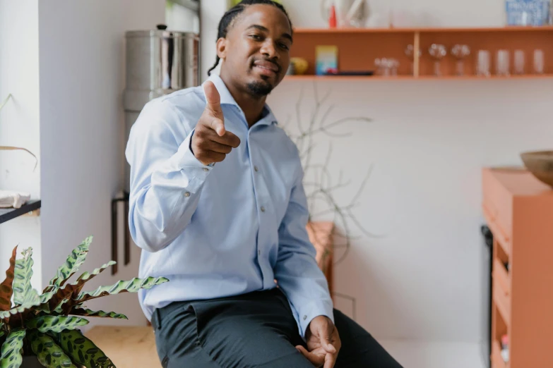 a man sitting on a stool giving a thumbs up, by Washington Allston, pexels contest winner, jemal shabazz, sitting in office, with pointing finger, profile image