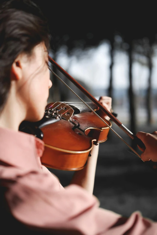 a woman in a pink shirt playing a violin, an album cover, by Elizabeth Durack, pexels contest winner, nature outside, profile pic, promo image, close - up photograph