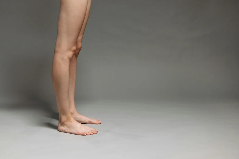 a woman standing in front of a gray background, by Marina Abramović, unsplash, hyperrealism, human legs, thin young male, ignant, hyper realistic background