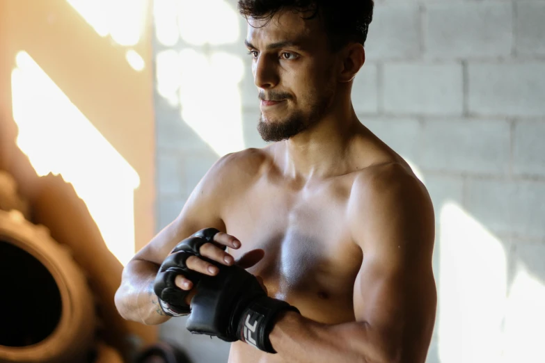 a shirtless man holding a pair of boxing gloves, a portrait, pexels contest winner, mma southpaw stance, profile image, indoor picture, handsome prince of persia