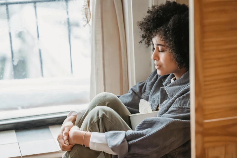 a woman sitting on the floor in front of a window, trending on pexels, comforting, ashteroth, looking off to the side, from waist up