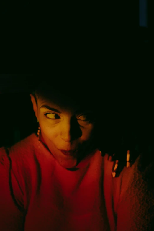 a woman sitting in front of a laptop computer, inspired by Nan Goldin, pexels contest winner, antipodeans, dramatic red scary lighting, portrait of willow smith, looking up at the camera, glowing yellow face