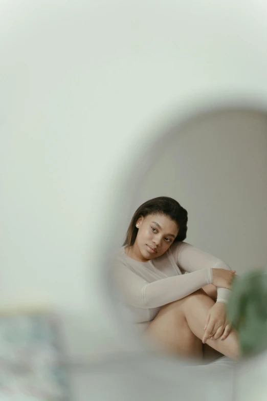 a woman sitting on a bed in front of a mirror, pexels contest winner, mixed race woman, on a pale background, sitting in a waiting room, soft oval face